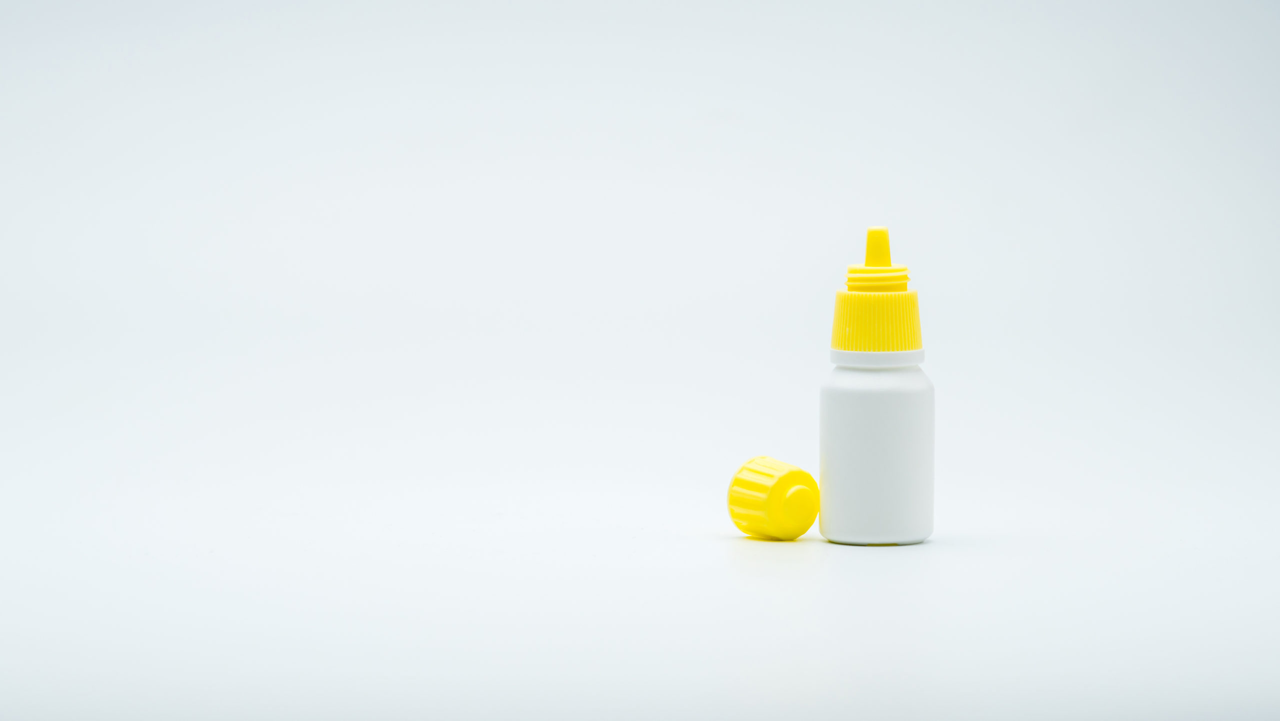 Eye drops bottle with open yellow cap isolated on white backgrou