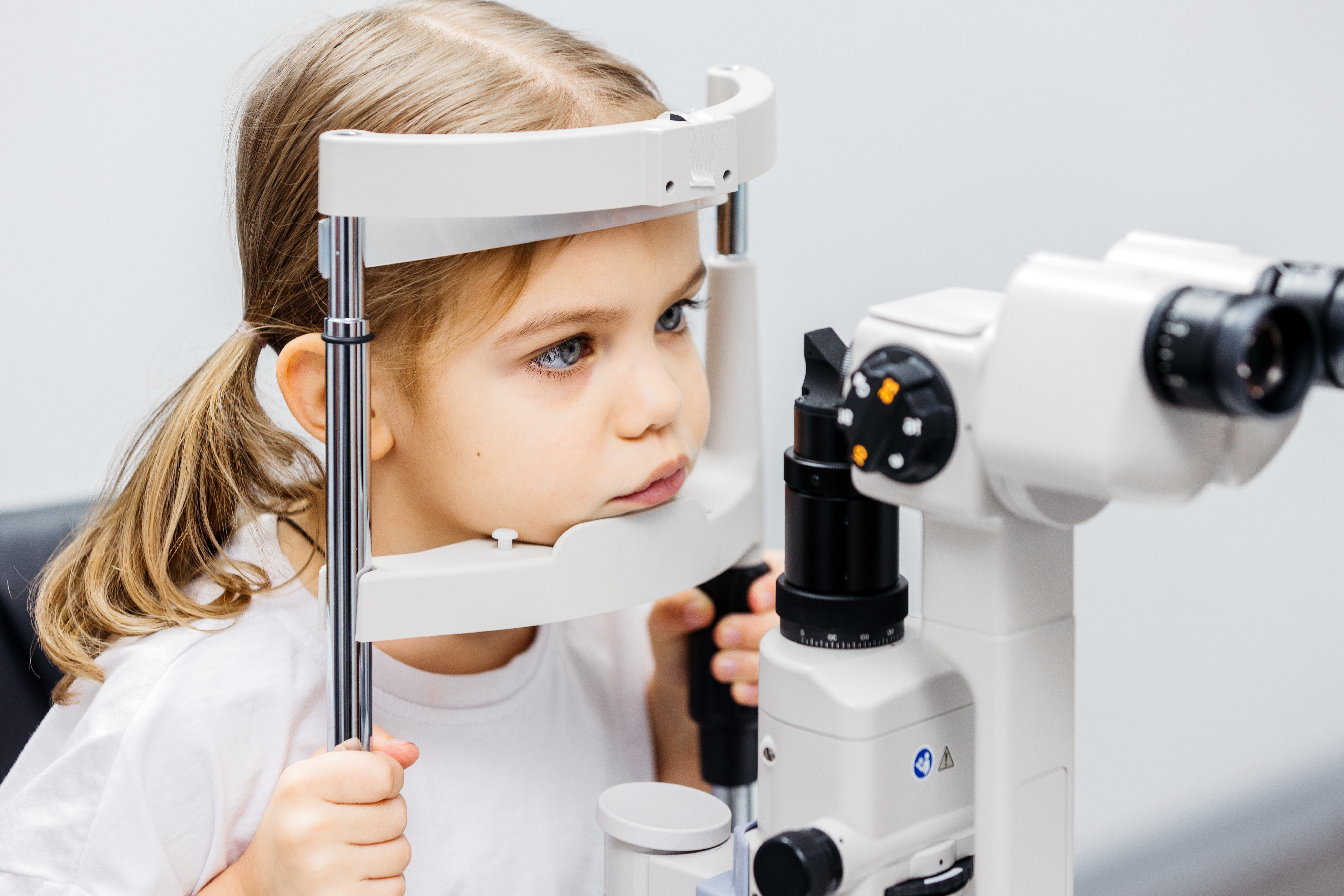 Young girl undergoing vision testing with advanced ophthalmic equipment, focused on eye examination process, showcasing the importance of pediatric eye care and early detection of vision issues